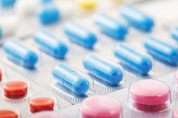 Heap of medical pills in white, blue and other colors. Pills in plastic package. Concept of healthcare and medicine.