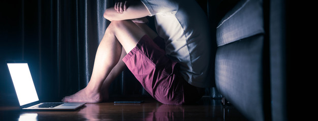 Scene of man use laptop alone in dark room conceptual of depression disorder, mental health issue...