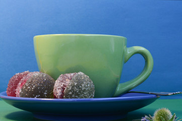  Blue-green mug with tea and two-color marmalade on a blue background