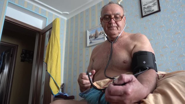 4K Mature man does his blood pressure with device at home
