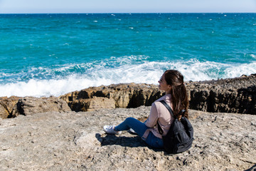 Beautiful woman sitting on the shore watching the waves