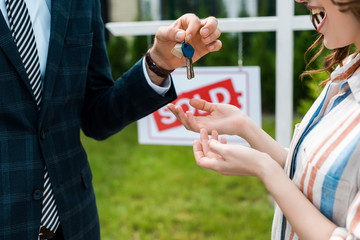 cropped view of realtor giving keys to happy woman