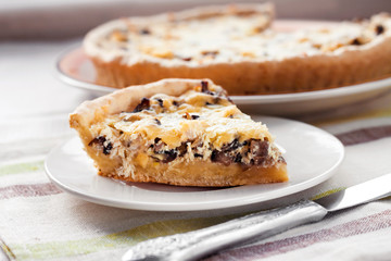 Slice of chicken tart with mushrooms and cheese on a plate