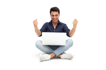 Excited handsome man feeling winner celebrating victory online business success and sitting on floor with laptop isolated on white background, Freelance concept