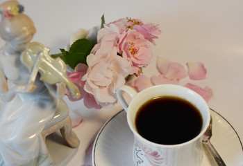  Beautiful tender still life in gently pink tones from a cup of coffee and a porcelain figurine of a girl playing the violin
