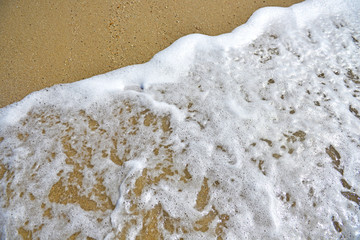 Onde sulla spiaggia con schiuma.