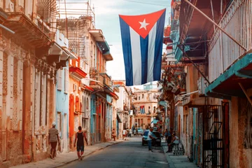 Fotobehang Cubaanse vlaggen, mensen en oude gebouwen in Oud Havana © kmiragaya