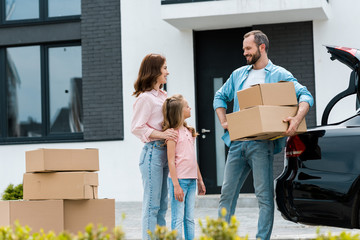 happy woman and kid looking at bearded man with boxes