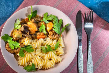 beef stew with vegetables and pasta spiral with greens