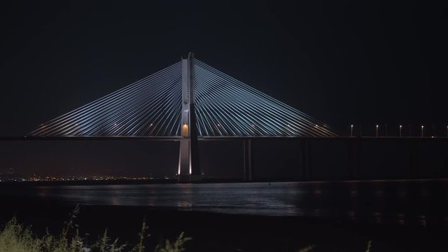 A fragment of the Vasco da Gama bridge in Portugal, shot at night, with rare cars, driving along it