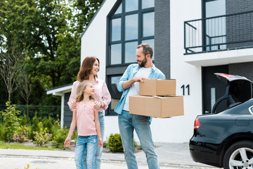 happy woman and kid looking at bearded man with boxes