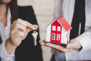 Young lady taking keys from female real estate agent during meeting after signing rental lease...