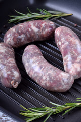 Raw meat sausages in a natural shell in a griddle pan prepared for cooking