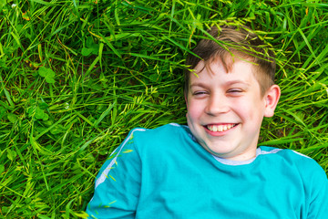 happy teen boy lying in the grass in summer