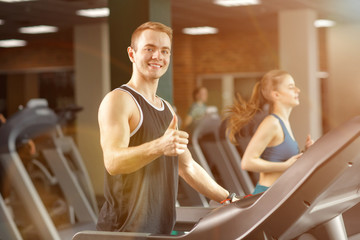 Young man  running on treadmill in gym doing cardio workout. - 274106965