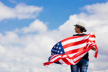 Woman holding the american flag outdoors on a meadow.  4th of July - Independence day.