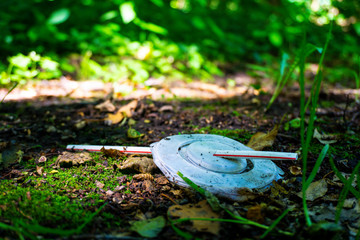 A plastic lid with straw lies at the edge in a wooded area, polluting the environment