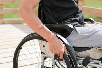 Disabled young athletic man on a wheelchair holding and turning wheels with hand engage in sports