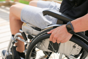 Obraz premium Niepełnosprawny młody atletyczny mężczyzna na wózku inwalidzkim, trzymając i obracając koła ręką uprawia sport