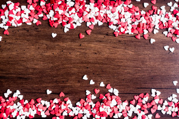 Valentines Day background with red and white hearts on a wooden table, top view. Red heart shaped candies on a wooden brown background. The concept of Valentines Day. 