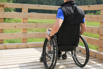 Disabled young man on a wheelchair holding and turning wheels with hand