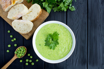 Pea soup  in the white bowl on the black wooden background.Top view.Copy space.