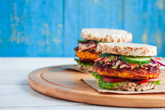 healthy vegan burgers with rice cracker  carrot cutlet lettuce coleslaw tomato cucumber on cutting board copy space