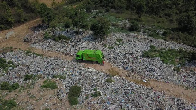The top view of the garbage truck is throwing garbage at the garbage bin.