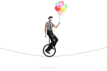 Pantomime man riding a unicycle on a rope, and holding a bunch of colorful balloons © Ljupco Smokovski