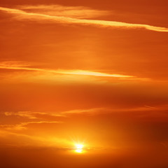 Beautiful cloudscape of orange colored sunset sky with shining sun