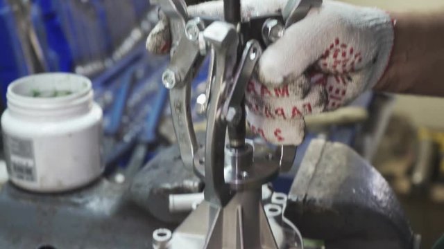Worker repairing a car part clamped in a vice closeup