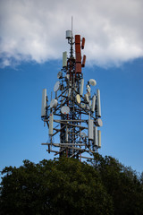 Cell antenna over the tree with cloudy sky