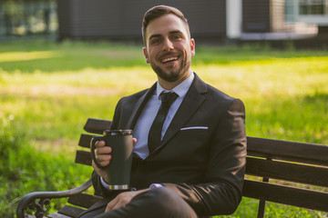 Fototapeta premium Elegant businessman enjoys drinking coffee while sitting outdoor.Toned image.