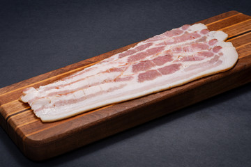Rashers of Uncured Apple Smoked Bacon arranged on natural wooden cutting board.