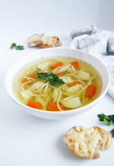 Russian chicken soup with carrots, potatoes, noodles on a light background. view top