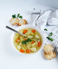 Russian chicken soup with carrots, potatoes, noodles on a light background. view top