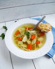 Russian chicken soup with carrots, potatoes, noodles on a light background. view top