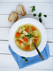Russian chicken soup with carrots, potatoes, noodles on a light background. view top