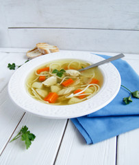 Russian chicken soup with carrots, potatoes, noodles on a light background. view top
