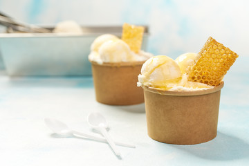 two portions vanilla ice cream in paper cup on mint colors background, selective focus