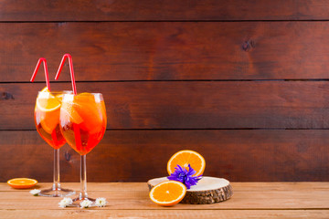 Cocktail aperol spritz on wooden boards. Summer alcoholic cocktail with orange slices and flowers....