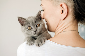 Beautiful young woman with cute cat resting at home. The British Shorthair