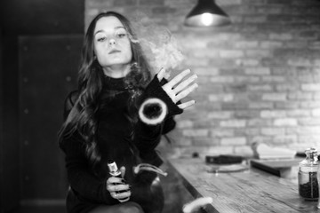 Fototapeta na wymiar Vaping teenager. Young pretty white girl smoking an electronic cigarette in vape bar. Bad habit. Black and white.