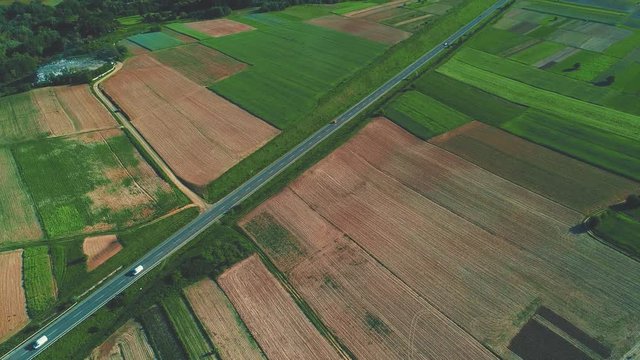 Beautiful landscape and village aerial with blue sky and clouds, a road, farmland and colorful fields. 4K.