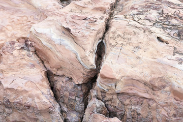 The rock is red with a fault in America. The crack in the stone, a piece of a broken stone brown color. Red stone with streaks of other colors.