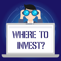 Text sign showing Where To Invest question. Business photo text asking about actions or process of making more money Man Holding and Looking into Binocular Behind Open Blank Space Laptop Screen