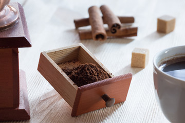 Ground coffee cinnamon sticks and cane sugar cubes on a wooden surface