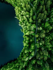 Foto op Plexiglas Aerial top view of country road in green summer forest and blue lake. Rural landscape in Finland. © nblxer