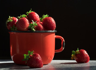 Fresh Strawberries in red enamel cup on black  background