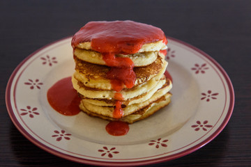 Stack of Homemade pancakes with freshly blended strawberries on plate.